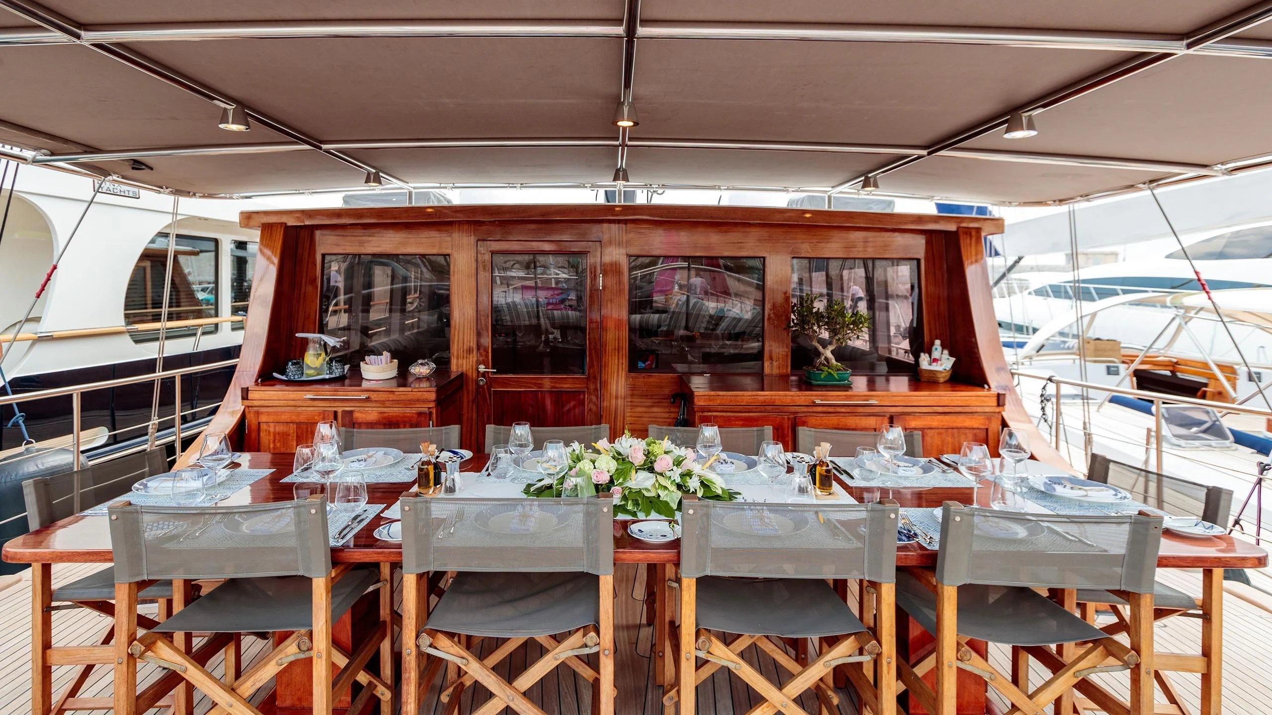 a dining table with chairs and a boat in the background aboard VITA DOLCE Yacht for Sale