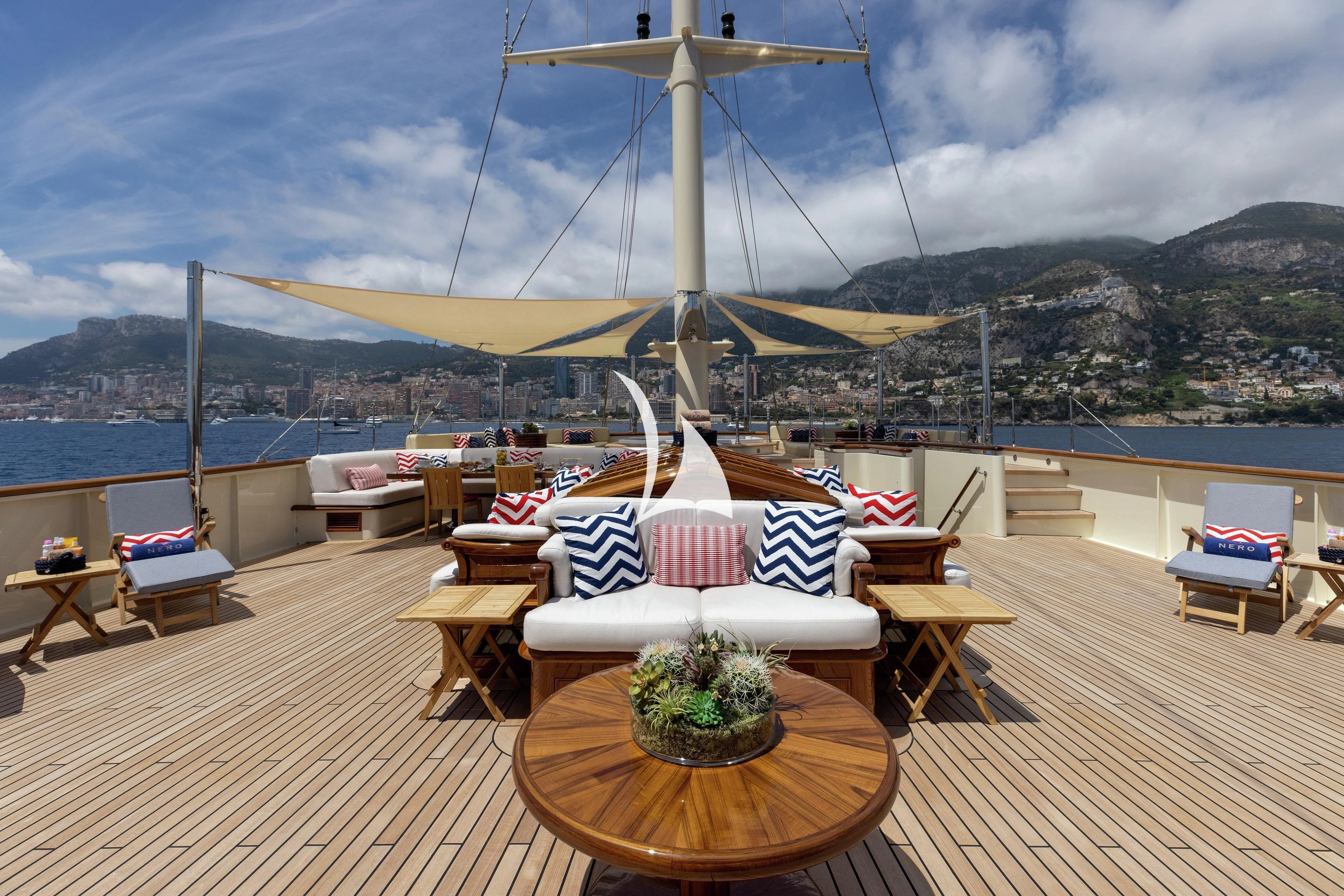 a deck with a table and chairs on it and a body of water in the background aboard NERO Yacht for Sale