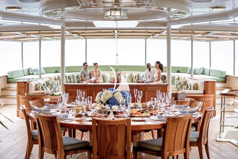 a group of people sitting at a table with food on it aboard NERO Yacht for Sale