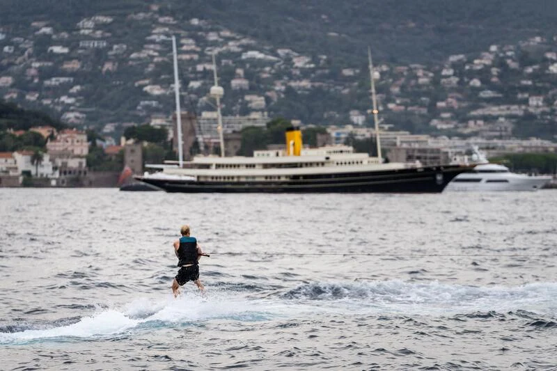 a man running in the water next to a large ship aboard NERO Yacht for Sale