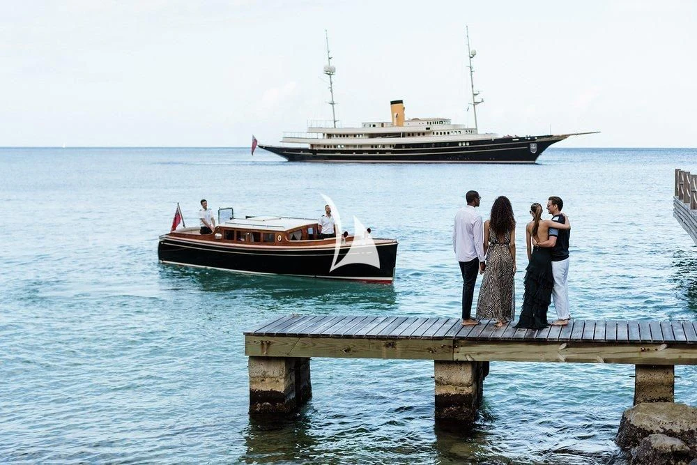 a group of people standing on a dock looking at a boat in the water aboard NERO Yacht for Sale