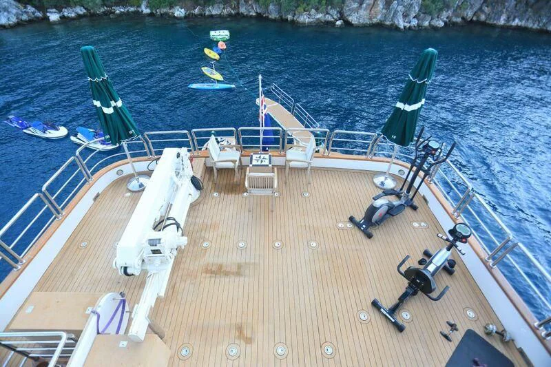 a person on a deck chair on a deck with a body of water and boats on it aboard FORTY LOVE Yacht for Charter