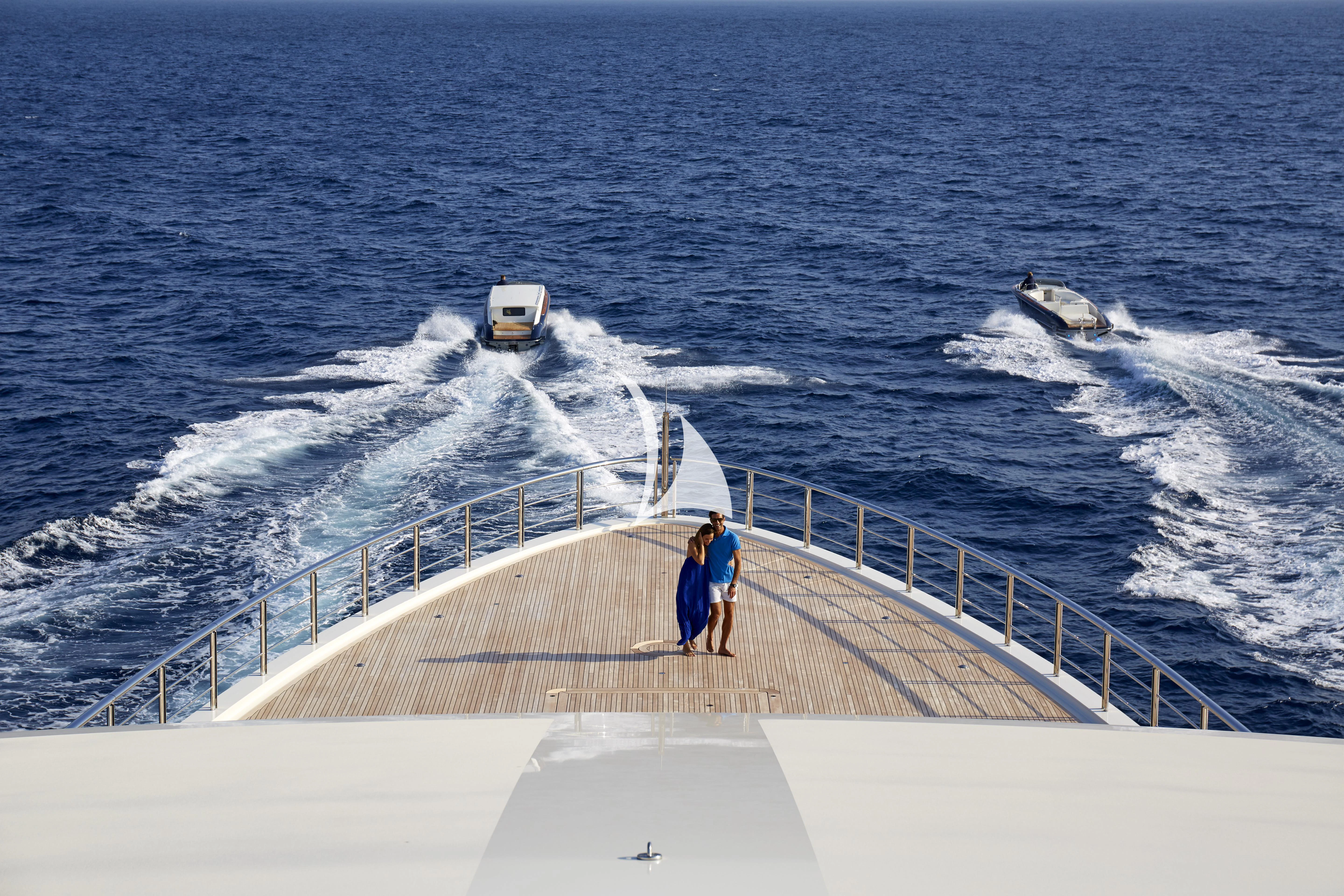 a man and a woman walking on a pier next to a boat aboard DRAAK Yacht for Sale