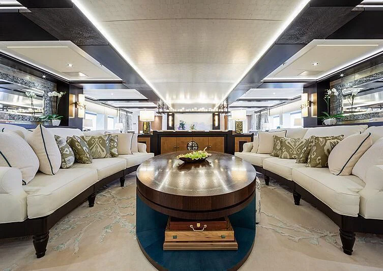 a living room with a large round table and couches aboard DRAAK Yacht for Sale