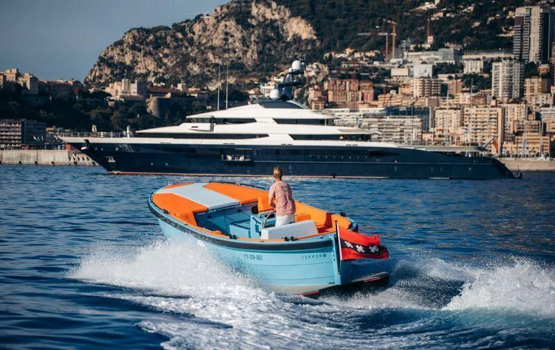 a person on a speedboat in the water with a city in the background aboard DRAAK Yacht for Sale