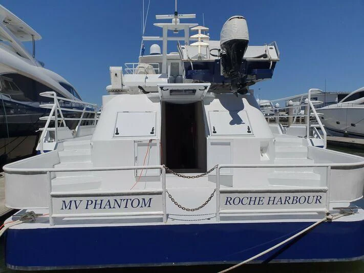 a white boat with a blue stripe aboard PHANTOM EXPLORER Yacht for Sale