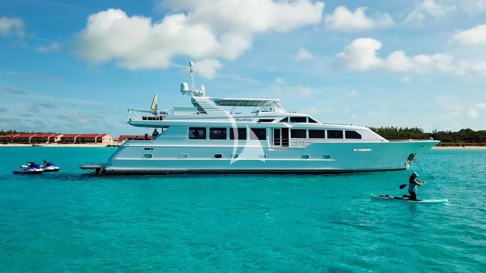 a person on a jet ski in the water next to a large white boat aboard ISLAND VIBE Yacht for Sale