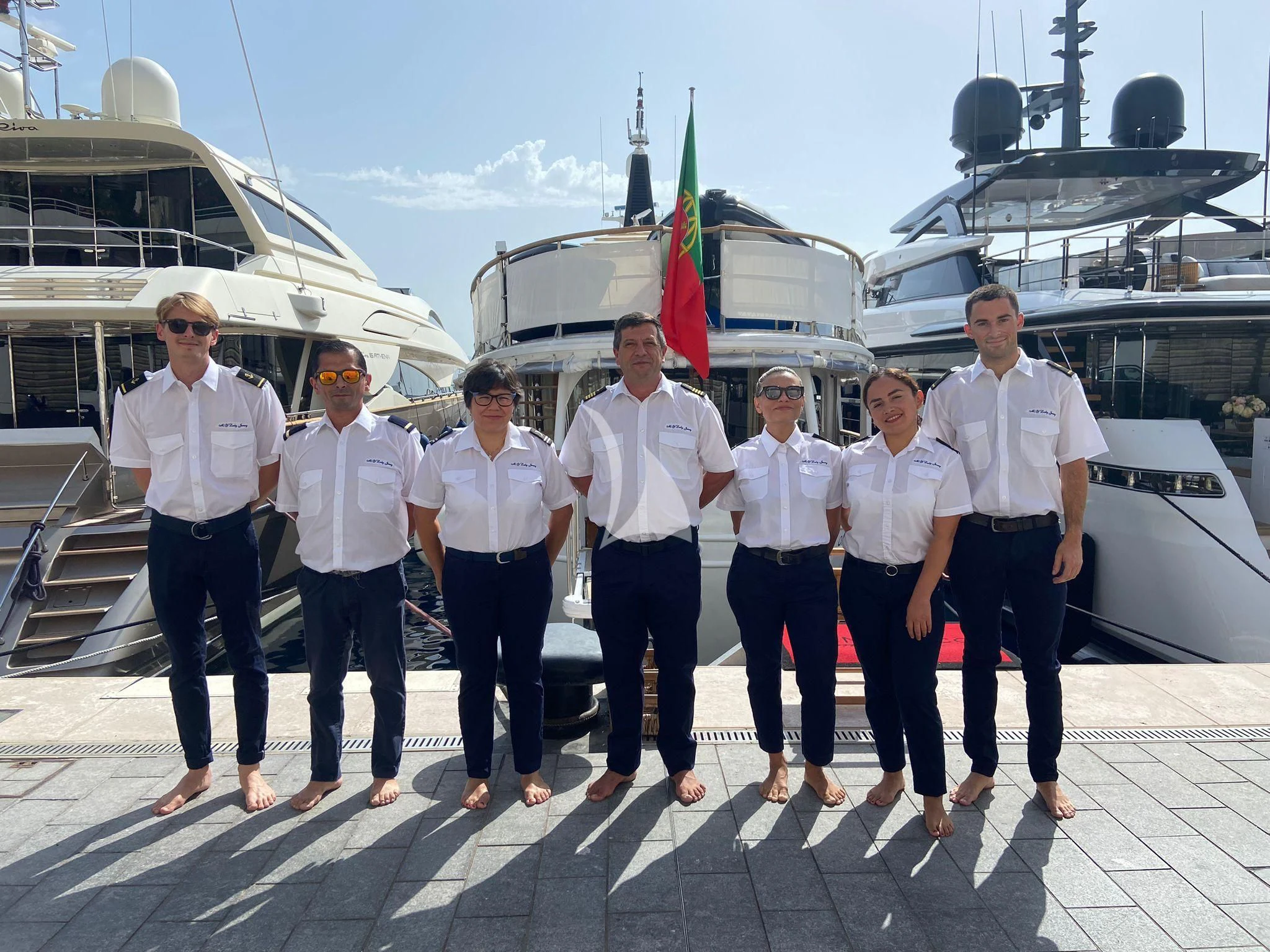 a group of people posing for a photo in front of a boat aboard LADY JERSEY Yacht for Charter