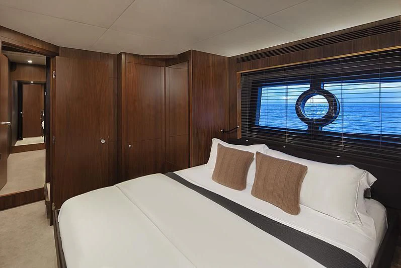 a bed with a white sheet and pillows in a room with a window aboard BRAVA Yacht for Sale