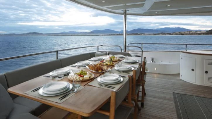 a table set for a meal on a deck overlooking the ocean aboard BRAVA Yacht for Sale