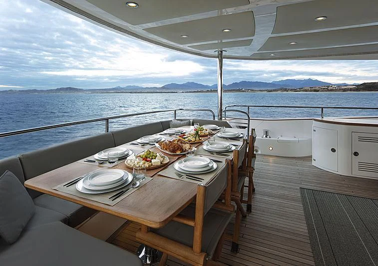 a table set for a meal on a deck overlooking the ocean aboard BRAVA Yacht for Sale