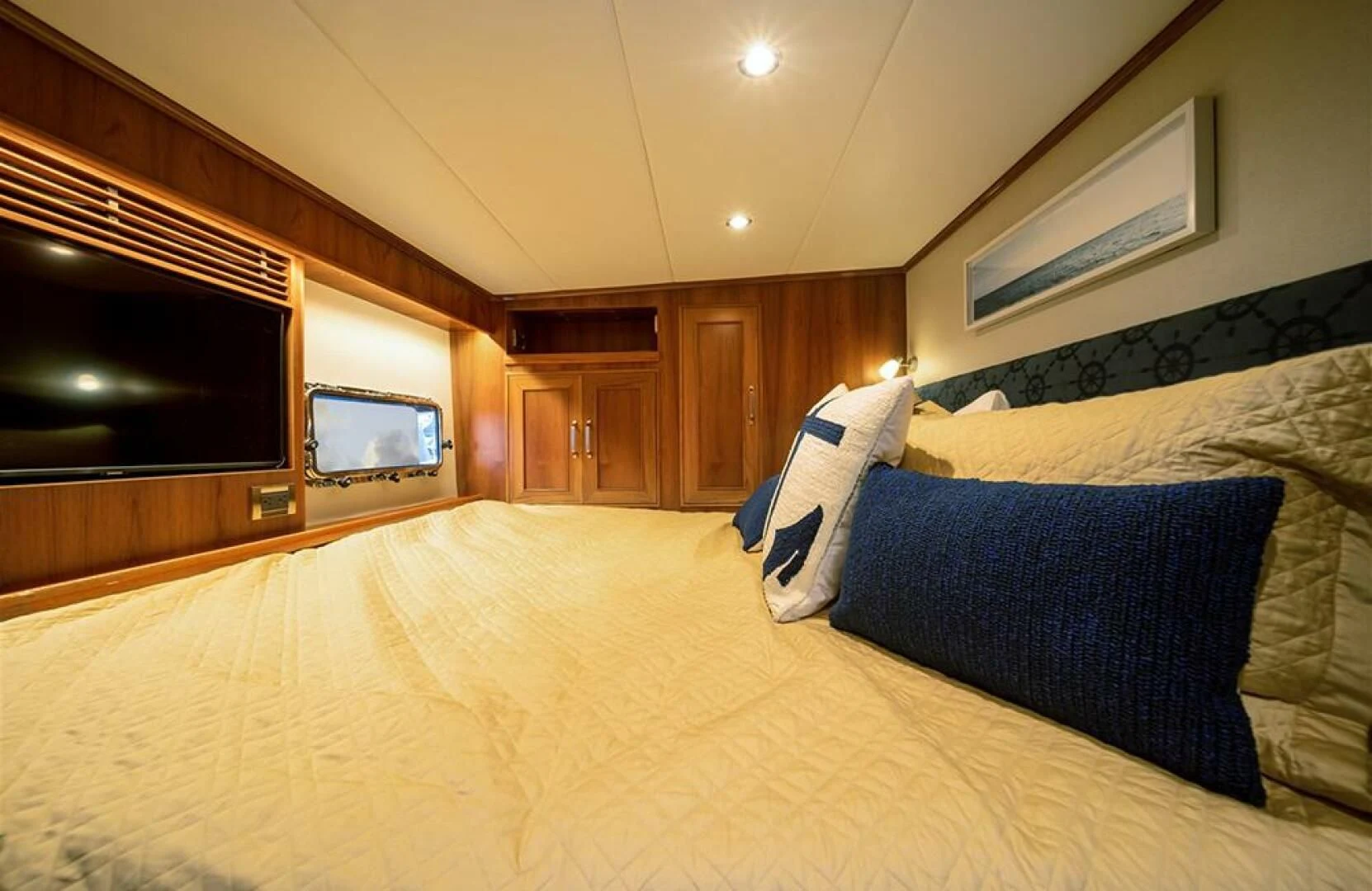 a bed with a blue and white pillow and a television on the wall aboard JULIANNE Yacht for Sale