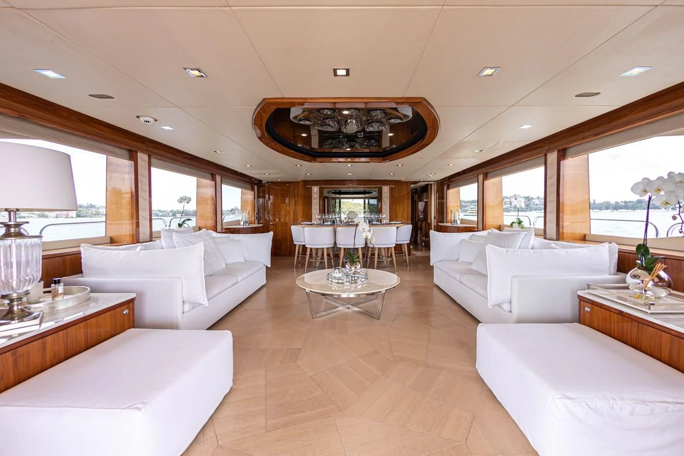 a large living room with white couches and a chandelier aboard CHAOS Yacht for Sale