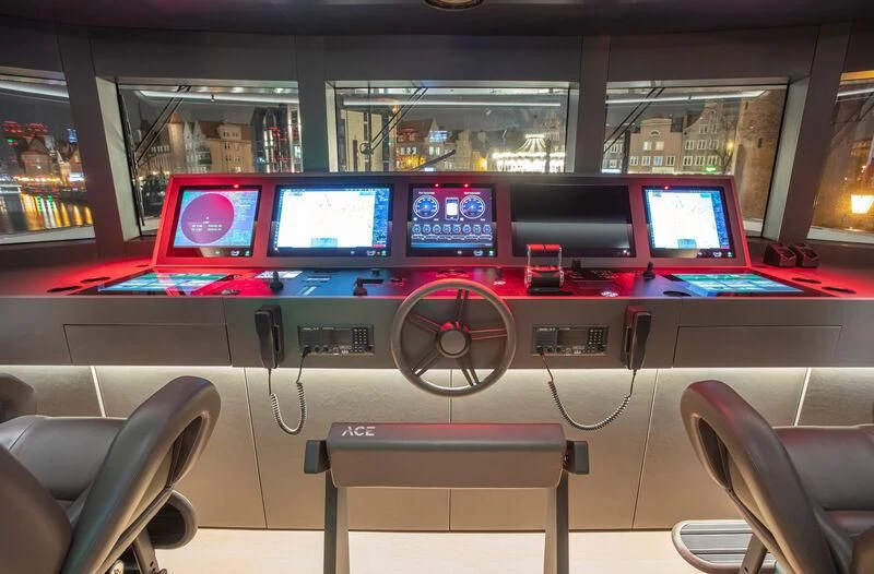 a row of computer screens on a table in a room with chairs aboard ACE Yacht for Sale