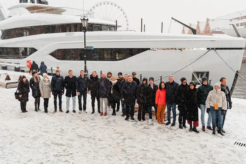 a group of people standing in front of a ski lodge aboard ACE Yacht for Sale