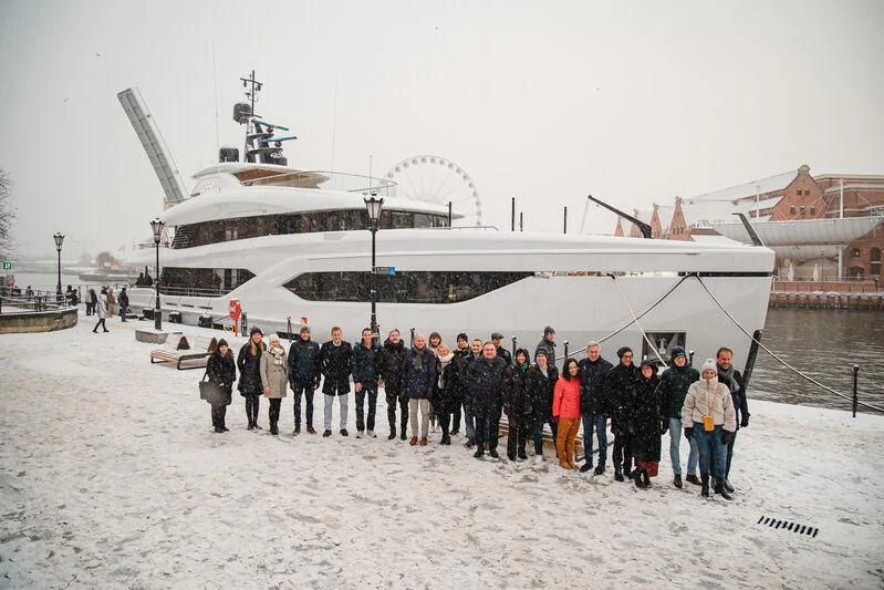 a group of people standing in front of a large ship aboard ACE Yacht for Sale