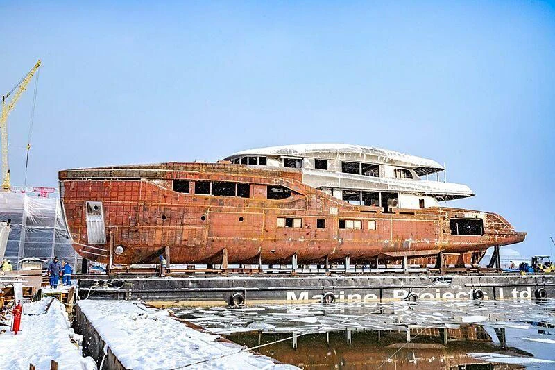 a large building with a lot of windows and a crane in the background aboard ACE Yacht for Sale