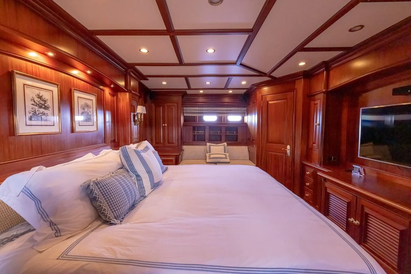a bed with a white sheet and pillows in a room with wood cabinets aboard 85 CLASSIC Yacht for Sale