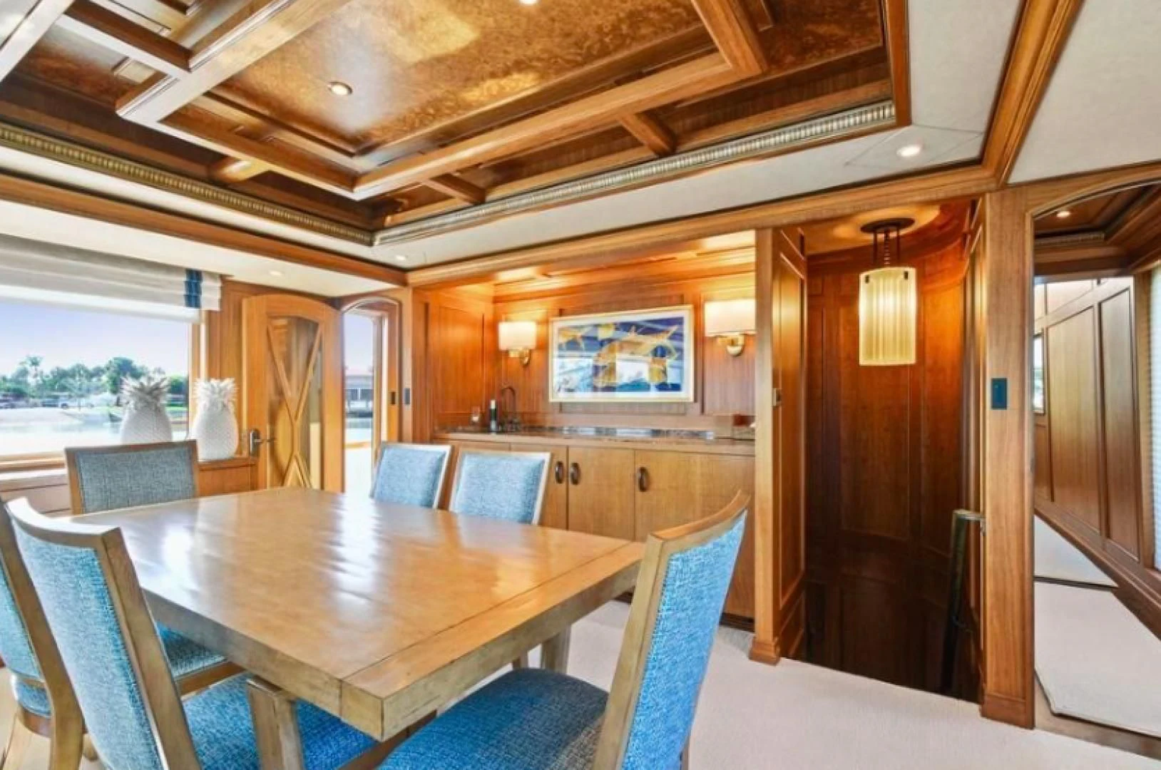 a wood table in a room with chairs and a large window aboard HAU TREE Yacht for Sale