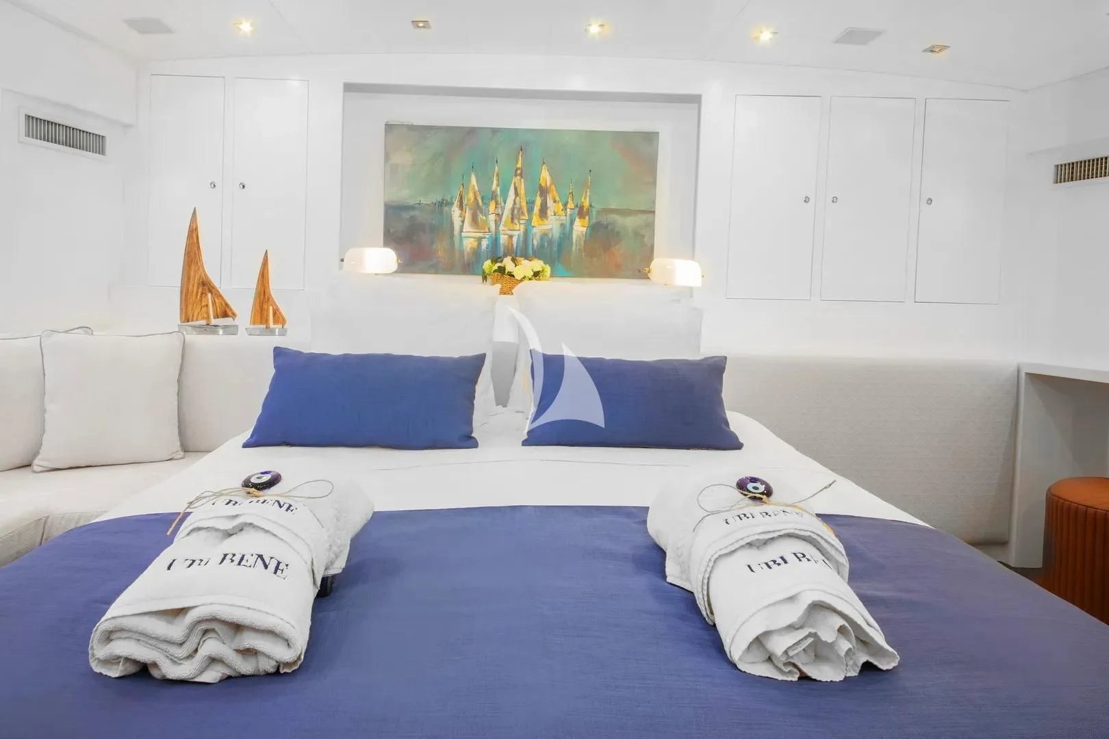 a large bed with blue and white pillows aboard UBI BENE Yacht for Charter
