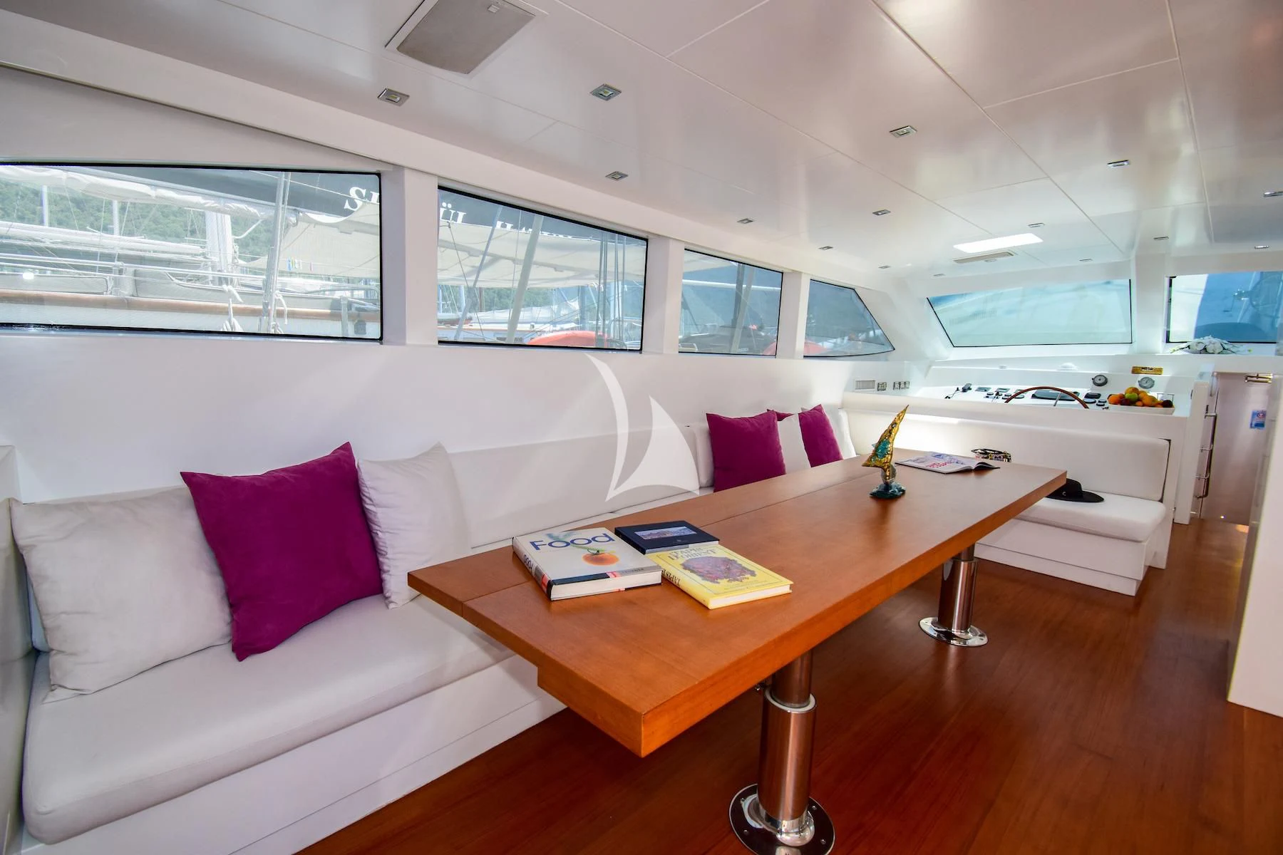 a room with a couch and a table with a book on it aboard UBI BENE Yacht for Charter