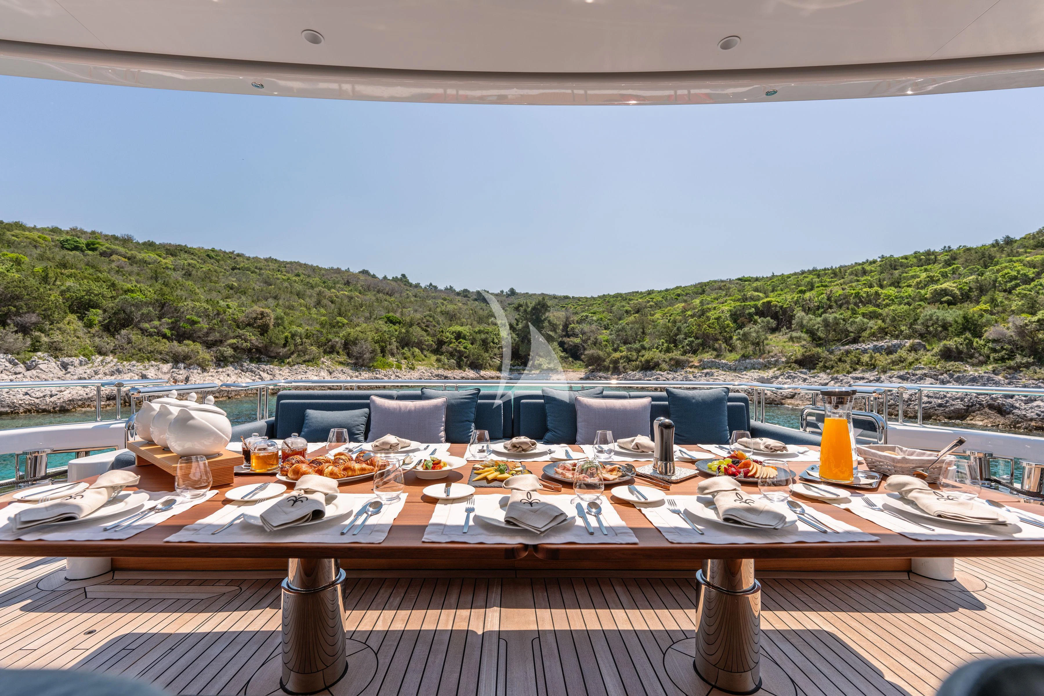 a table set for a meal on a deck overlooking a large body of water aboard TIREA Yacht for Sale