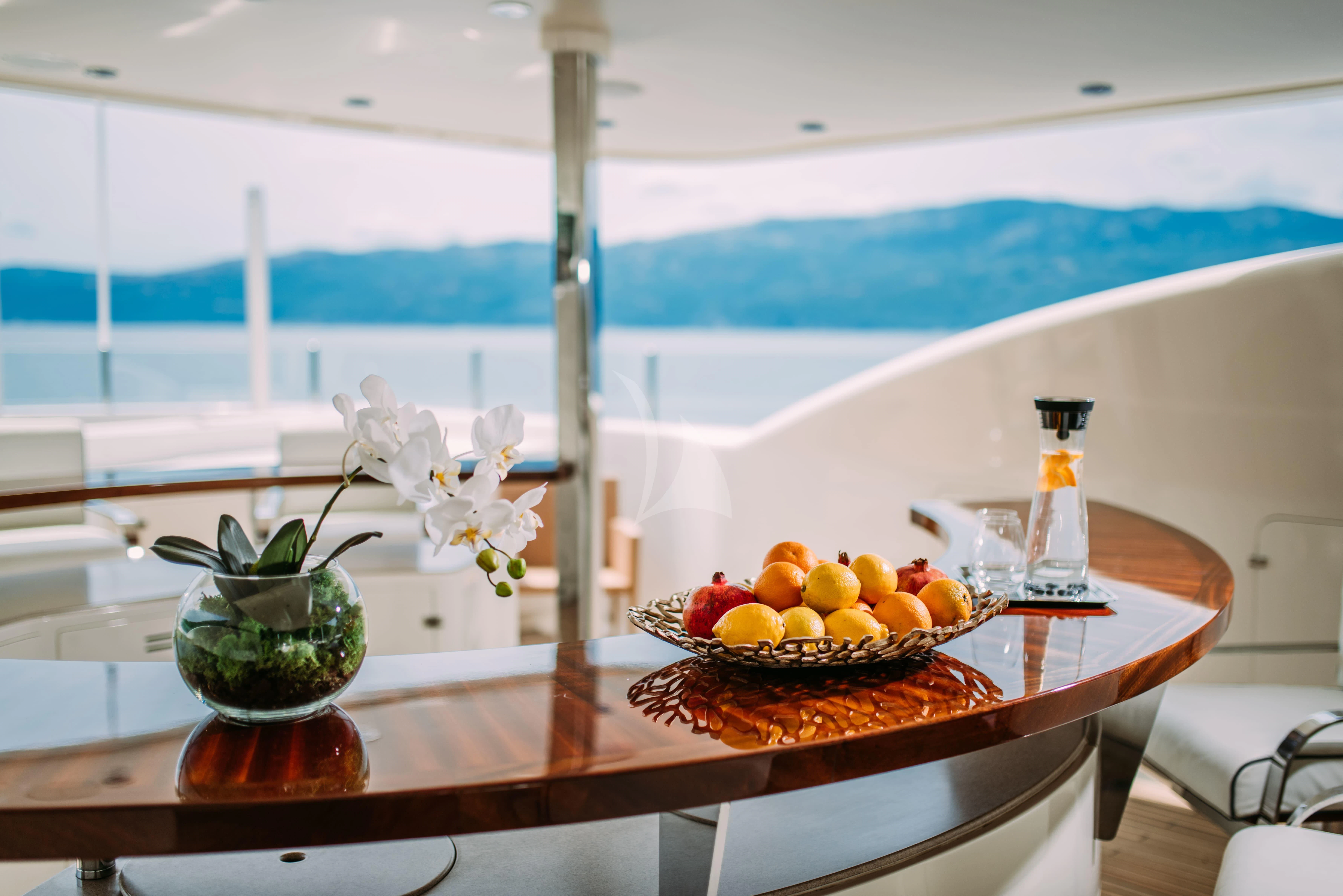 a table with a vase of fruit and a bottle of wine aboard TIREA Yacht for Sale