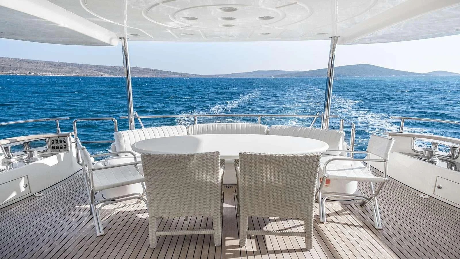 a table and chairs on a deck overlooking the ocean aboard TITAN Yacht for Sale