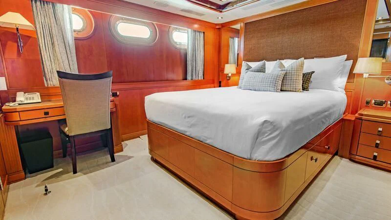 a room with a bed and desk aboard PLEIADES II Yacht for Sale