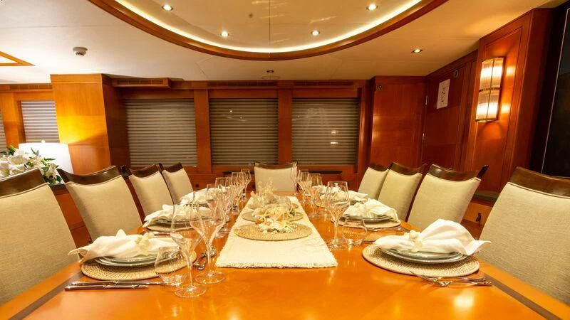 a large dining table with a large white tablecloth and chairs aboard PLEIADES II Yacht for Sale