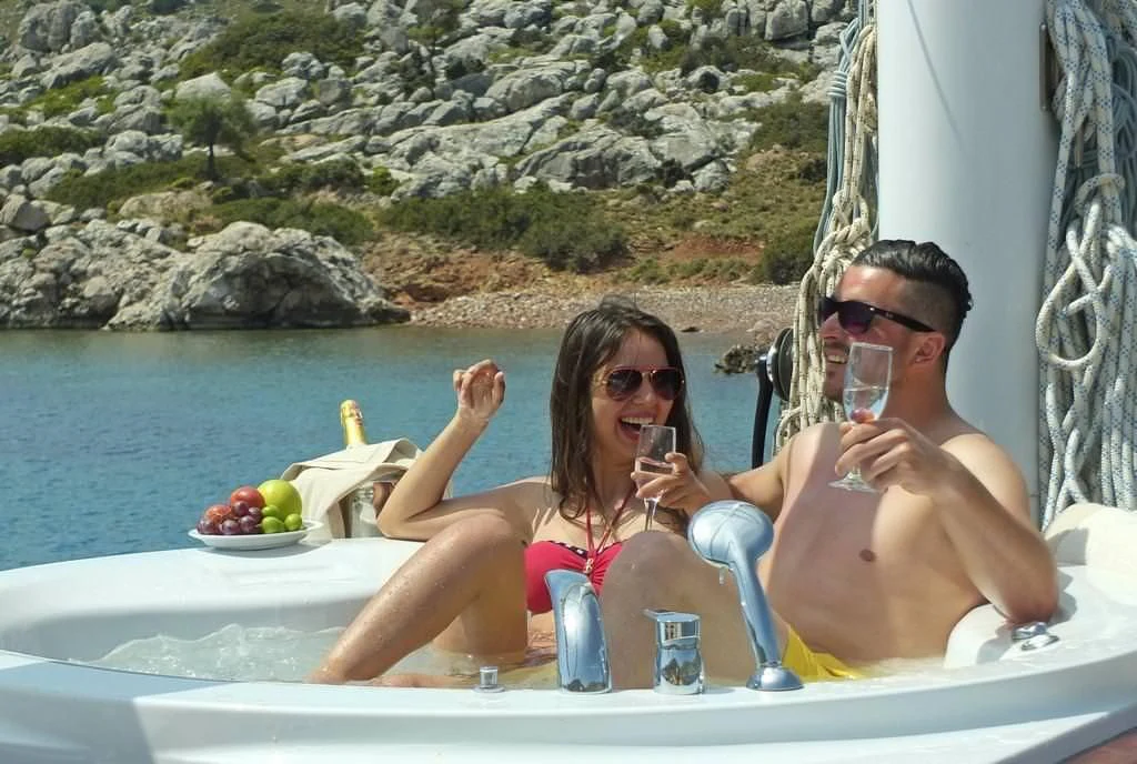 a couple of women sitting in a pool with drinks and a rocky cliff aboard KAPTAN MEHMET BUGRA Yacht for Sale