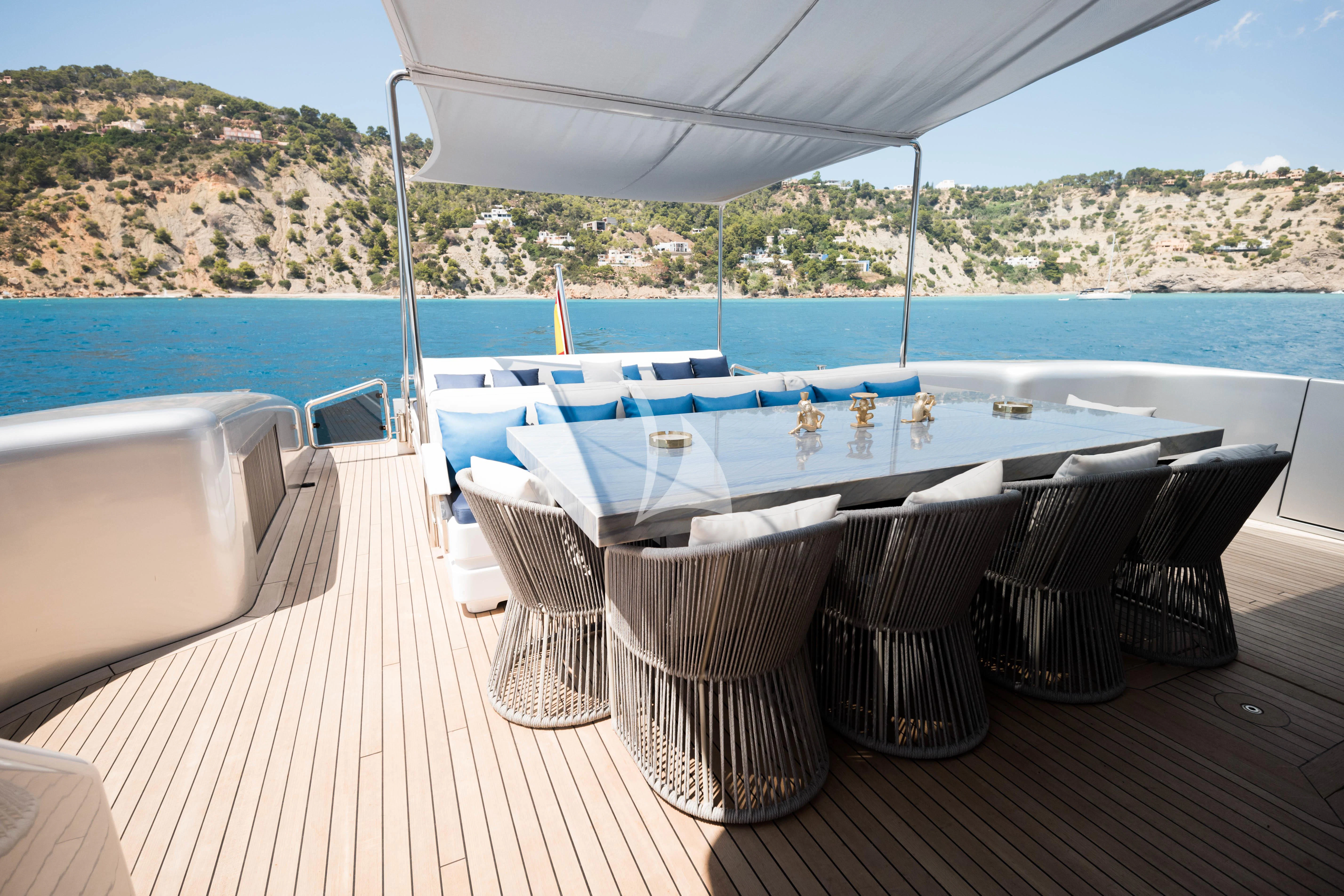 a table and chairs on a deck overlooking a large body of water aboard EVA Yacht for Charter