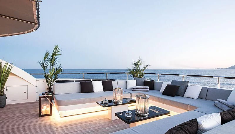 a living room with a large blue sofa and a table with a glass of water and a tree aboard GEMS 2 Yacht for Sale