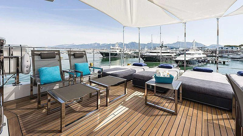 a deck with a table chairs and a bed on it aboard ABVIOS Yacht for Sale