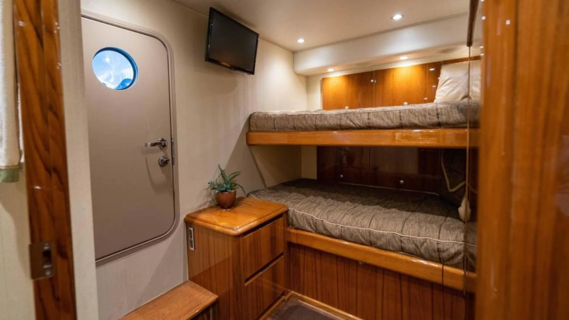 a bedroom with a bed and a tv on the wall aboard NEVER TOO LATE Yacht for Charter