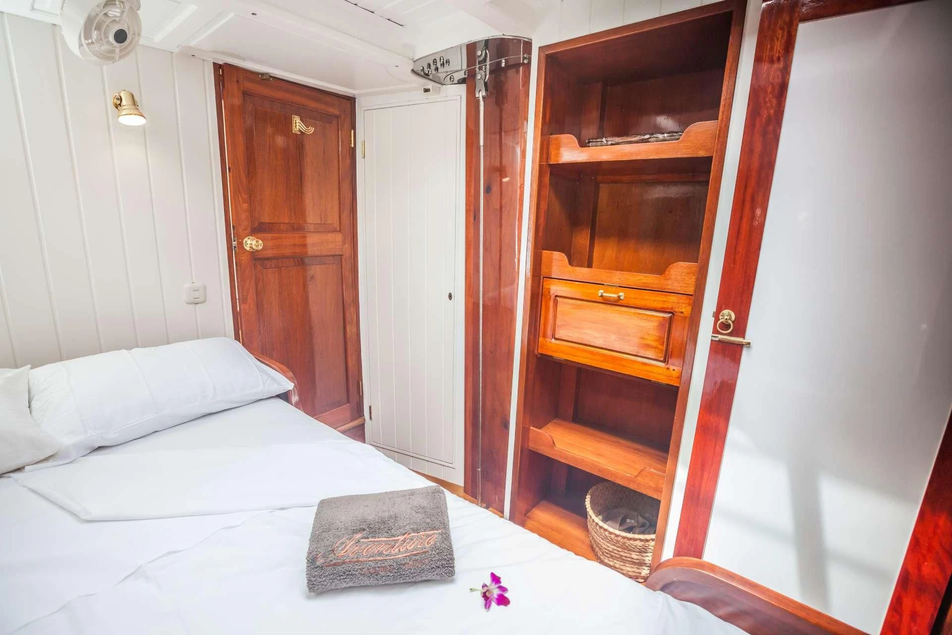 a bed with a white sheet on it and a wooden door aboard AVENTURE Yacht for Sale