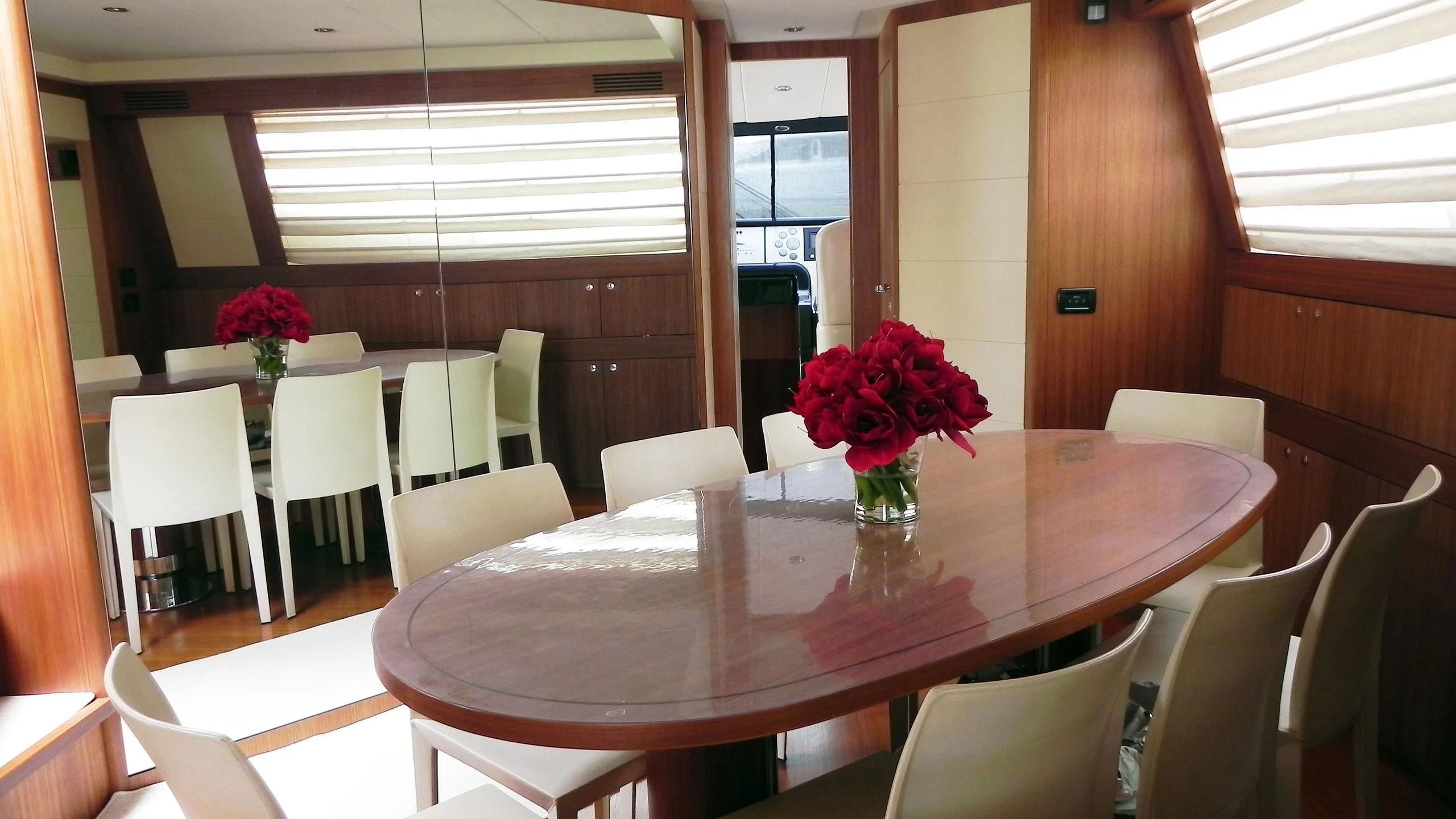 a table with white chairs and red flowers in a room with wood walls aboard WEDGE THREE Yacht for Sale