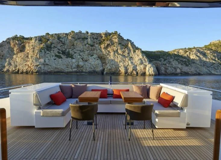 a deck with chairs and a large rock formation in the background aboard AMAN Yacht for Sale