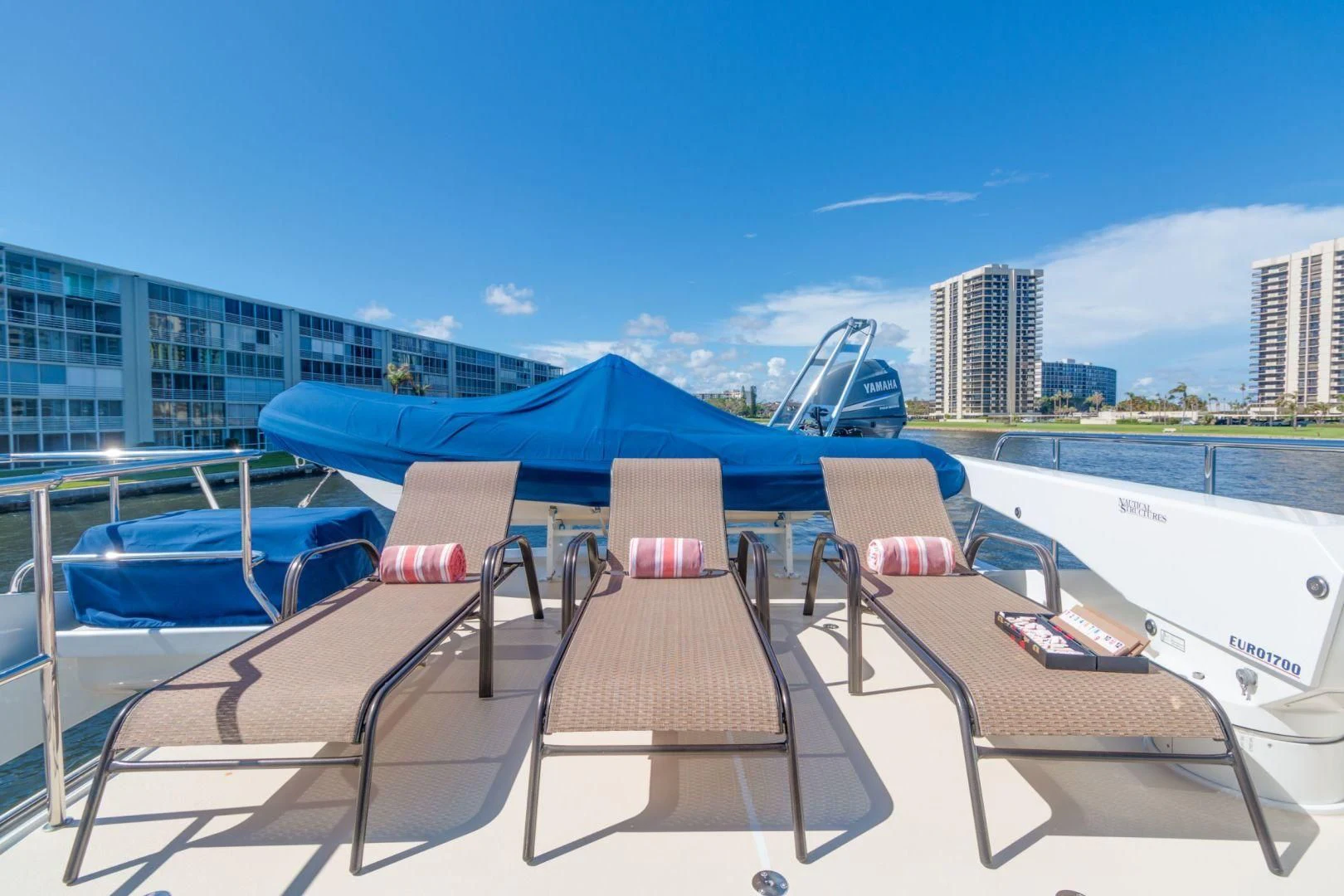 a table with chairs on it next to a pool with a city in the background aboard WINDWARD Yacht for Charter