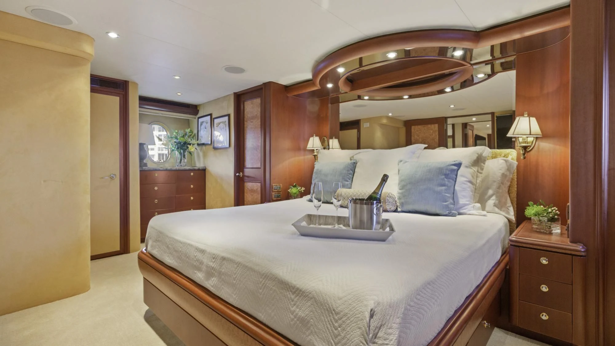 a bed with a white sheet and pillows in a room with wood cabinets aboard WINDWARD Yacht for Charter