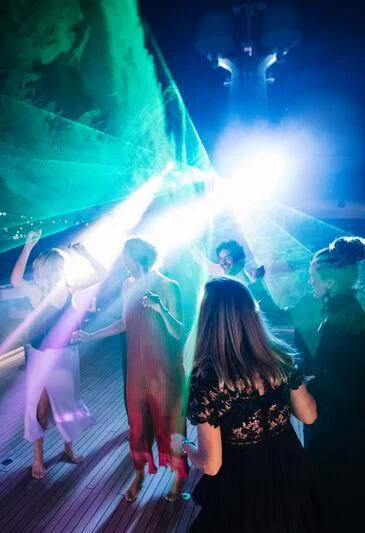 a group of people in a large room with a large green light aboard WHEELS Yacht for Sale