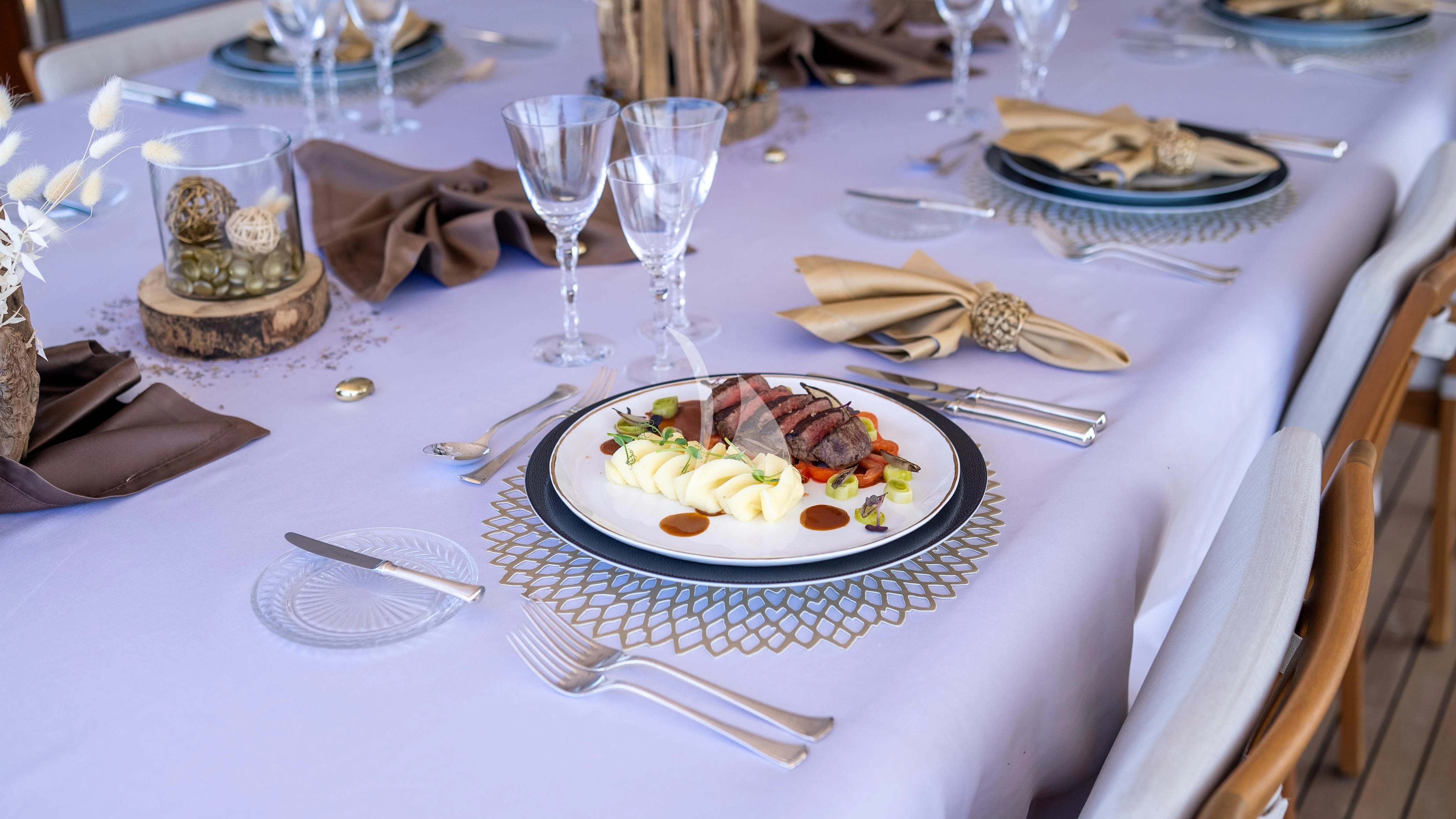 a table with plates of food and silverware aboard WHEELS Yacht for Sale