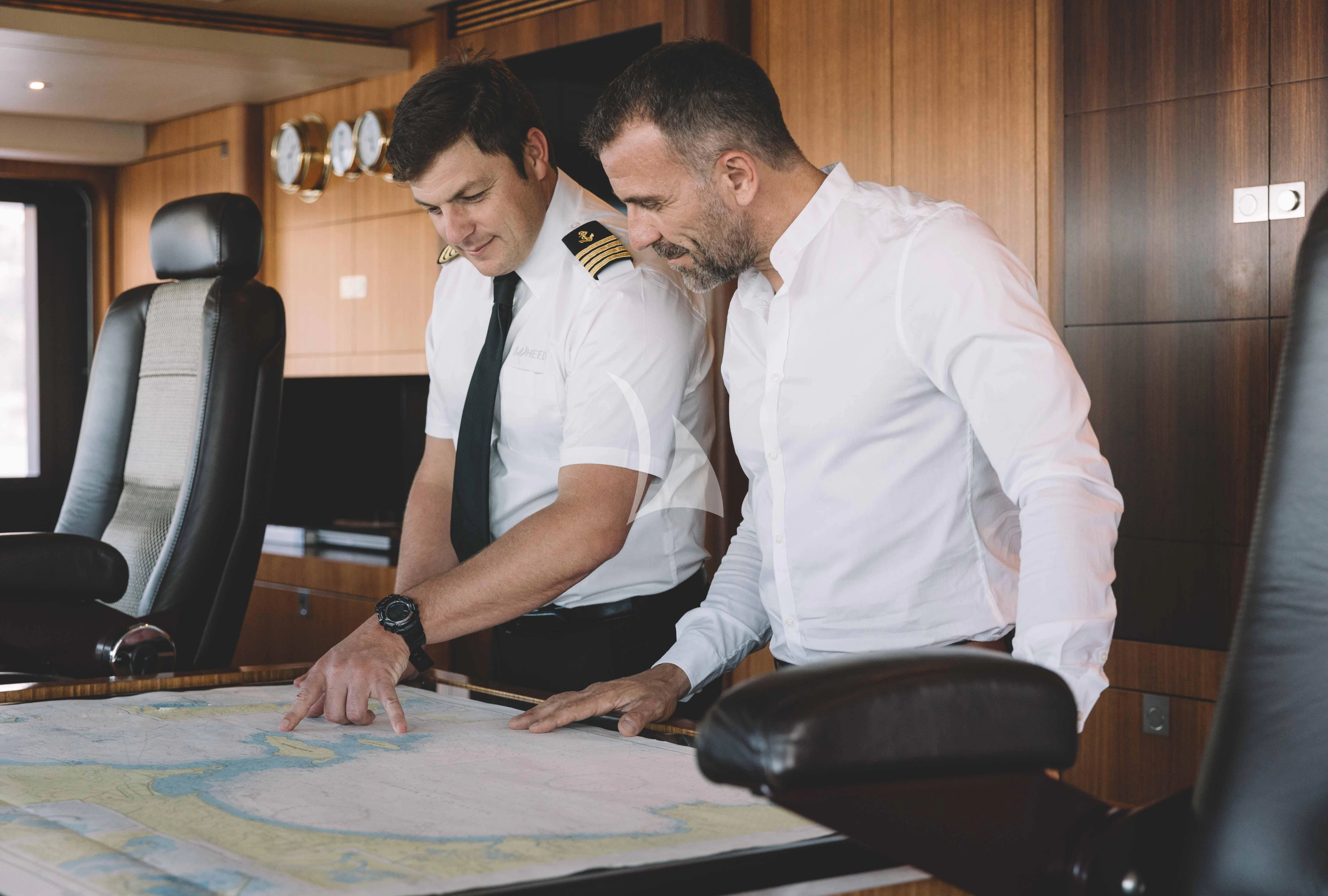 a group of men looking at a computer screen aboard WHEELS Yacht for Sale