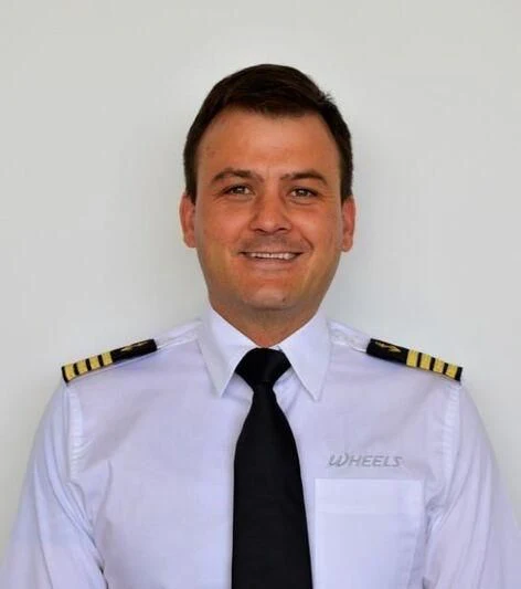 a man in a white shirt and tie aboard WHEELS Yacht for Sale