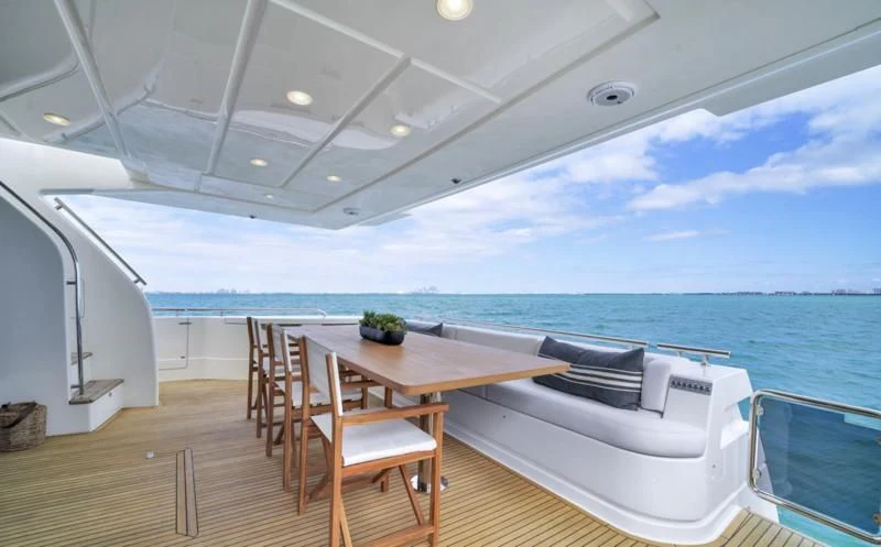 a table and chairs on a deck overlooking the ocean aboard BON BON Yacht for Sale