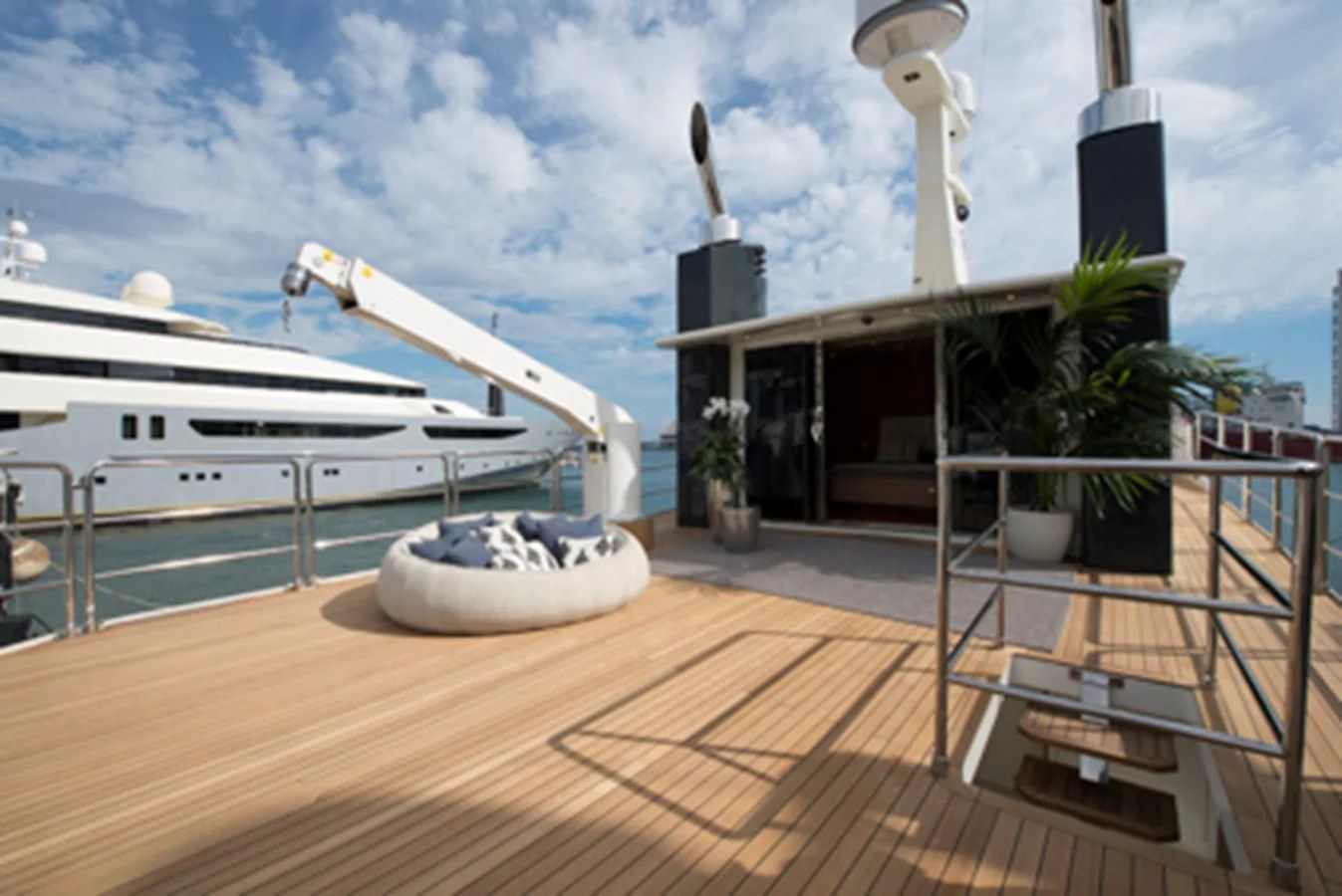 a deck with a boat and a large white boat in the water aboard BULLY Yacht for Sale