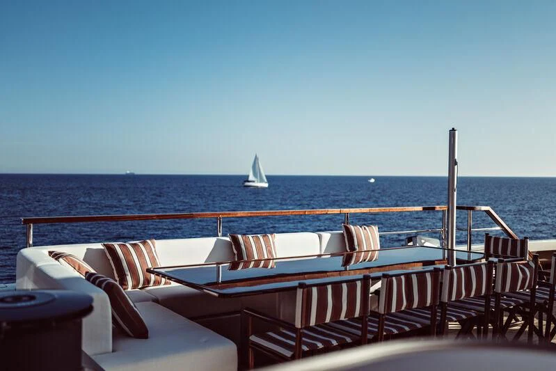 a deck with chairs and tables on it by the ocean aboard ARTEXPLORER Yacht for Sale