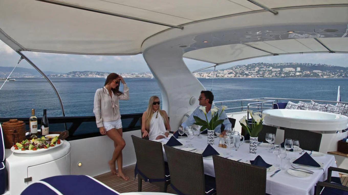 a couple of people sitting at a table with food and drinks on it aboard ASHA Yacht for Sale