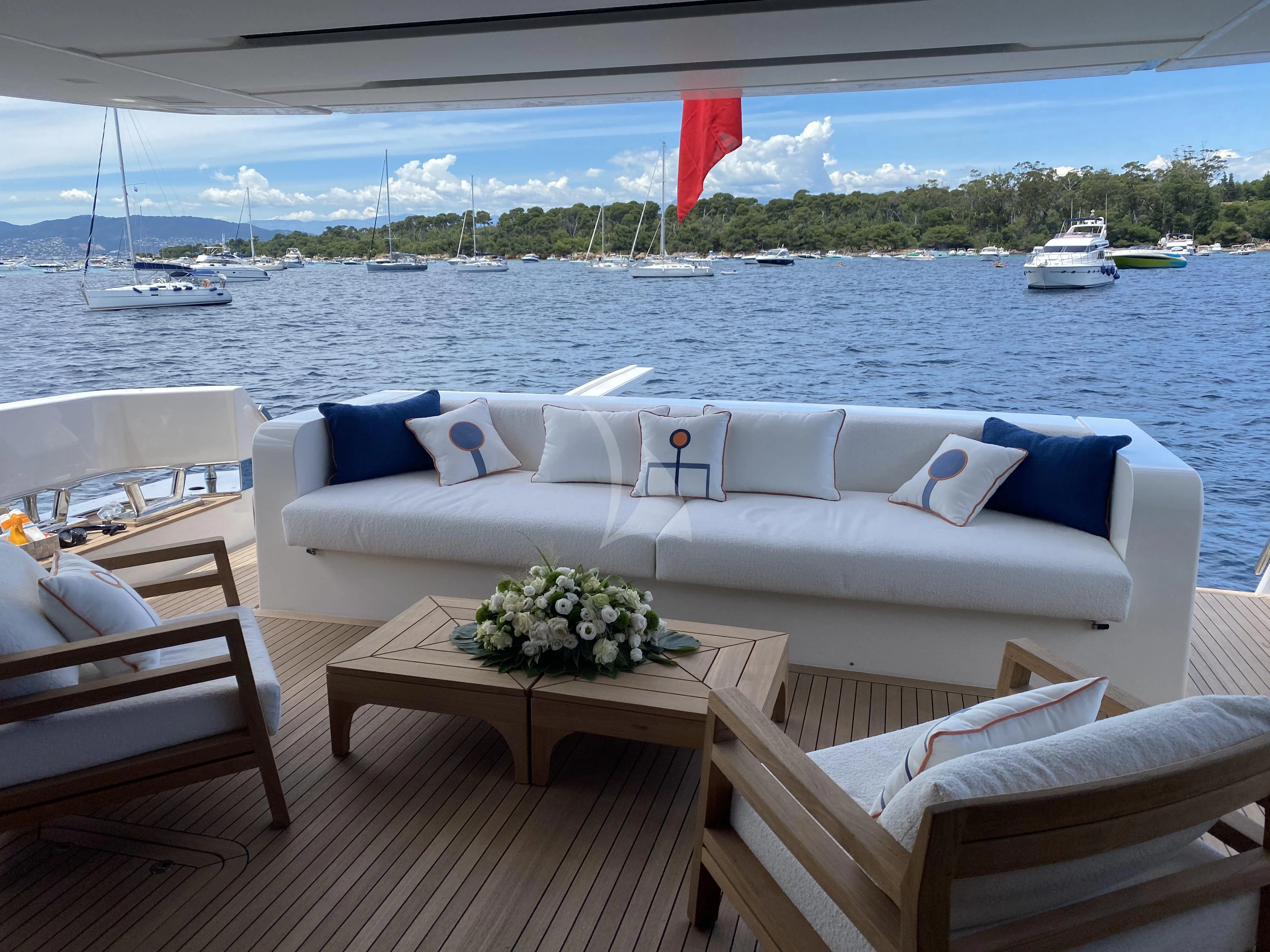 a white couch with a table and chairs on a deck overlooking a body of water aboard REINE D'AZUR Yacht for Sale