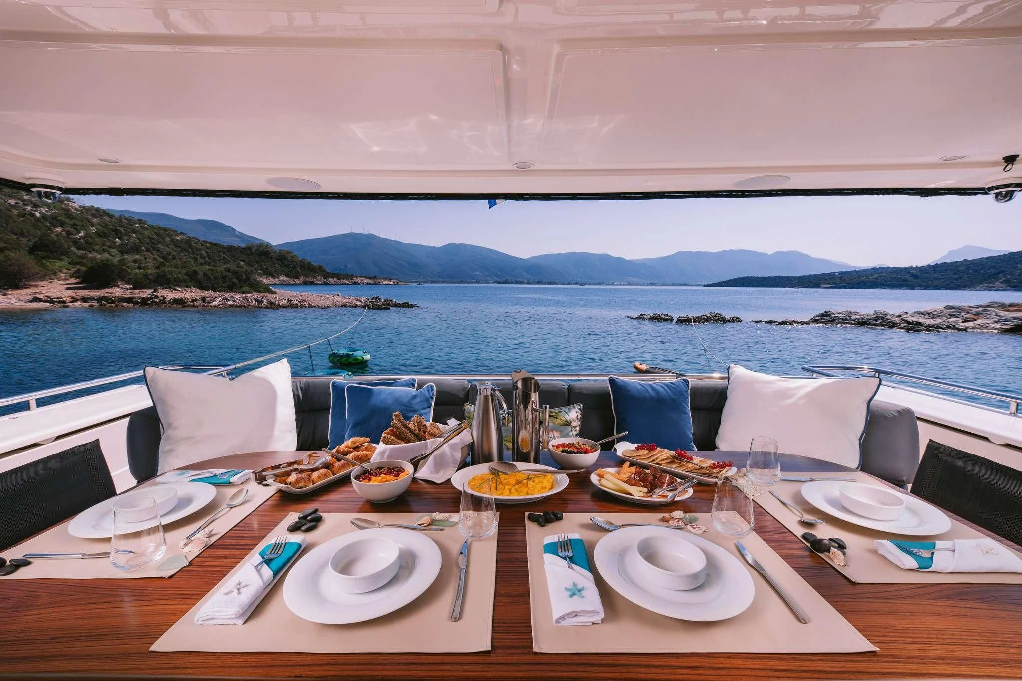 a table with plates and food on it by a body of water aboard OXYGEN 8 Yacht for Charter